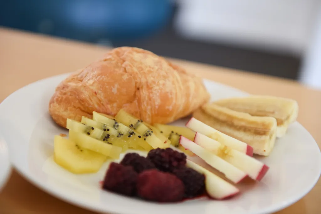 Fresh croissant with sliced kiwifruit, apple, banana and berries