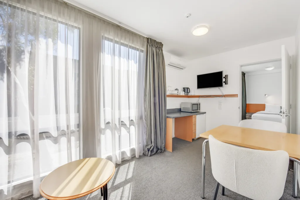 Courtyard Suite living area with dining table, tea and coffee, TV and separate bedroom
