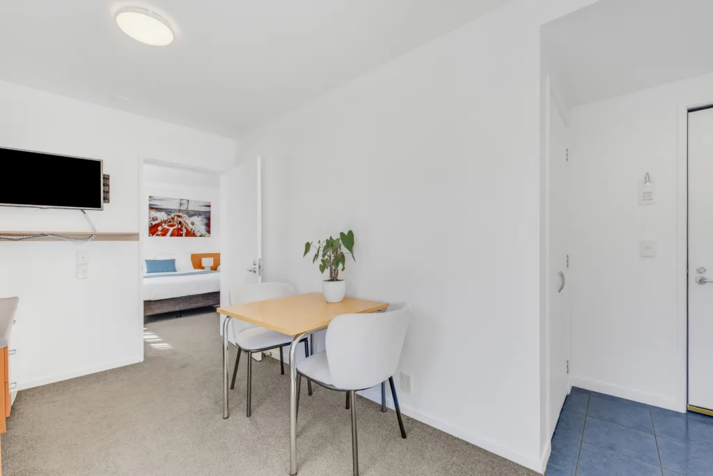 Courtyard Suite dining table and TV, with the bedroom through an open door