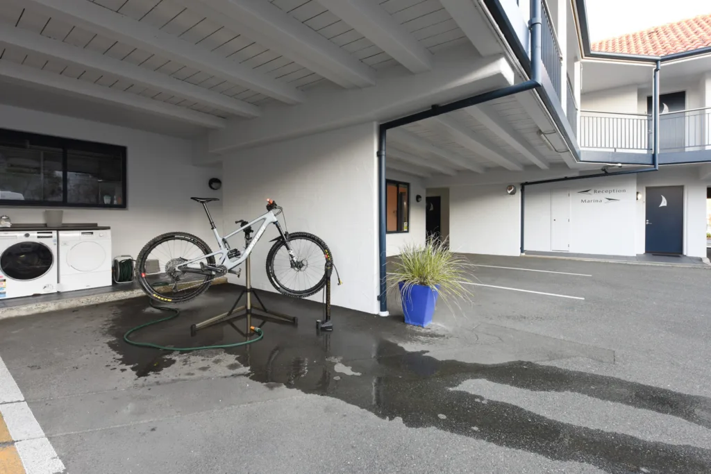 Covered bike wash area with work stand and hose, beside the guest laundry washer and dryer