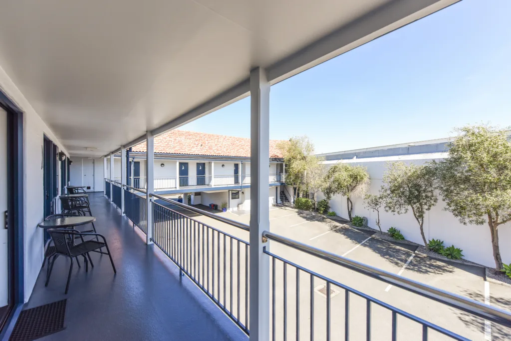 Upper walkway with bistro tables overlooking the olive-lined courtyard
