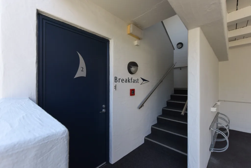 Stairs to the breakfast room beside a navy guest room door with bike racks