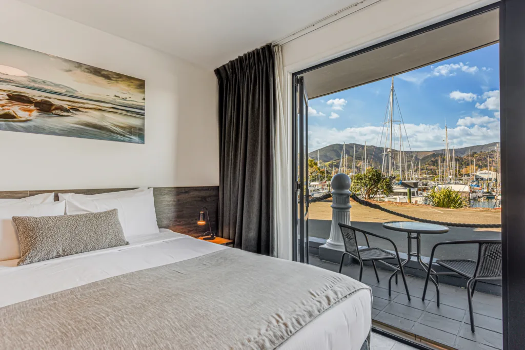 Super king bed beside open doors to a private patio and Nelson Marina