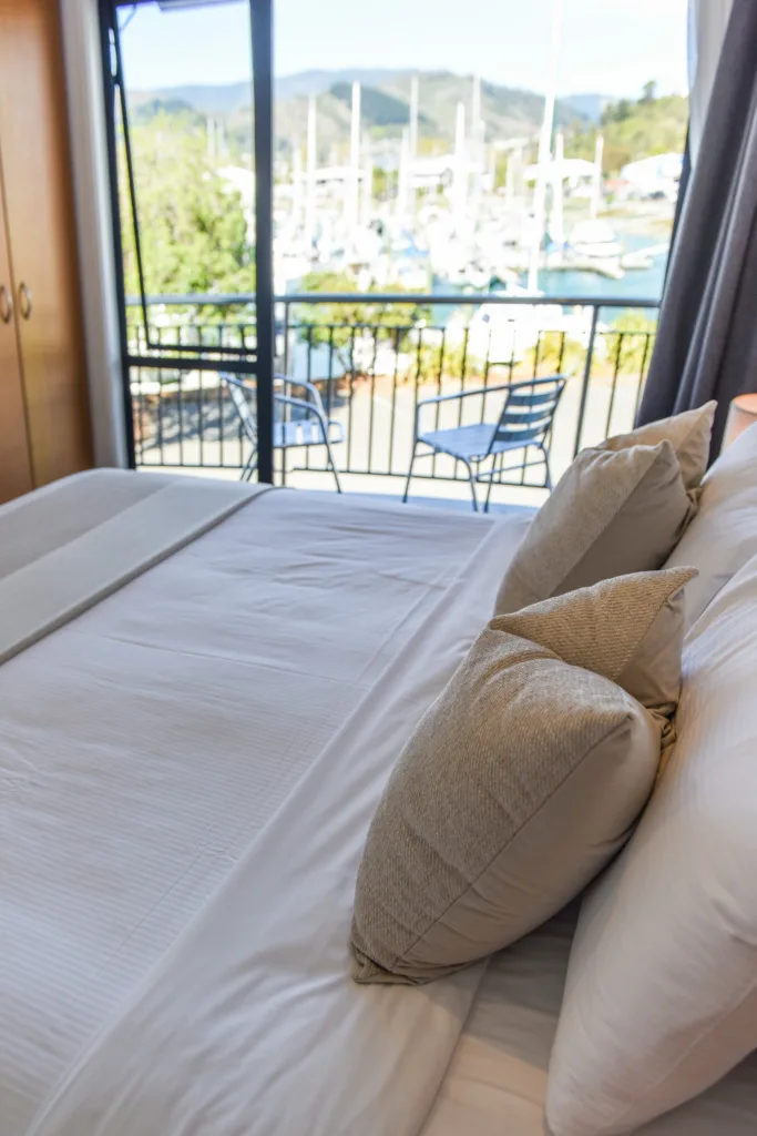 Super king bed with open doors to a balcony and marina view